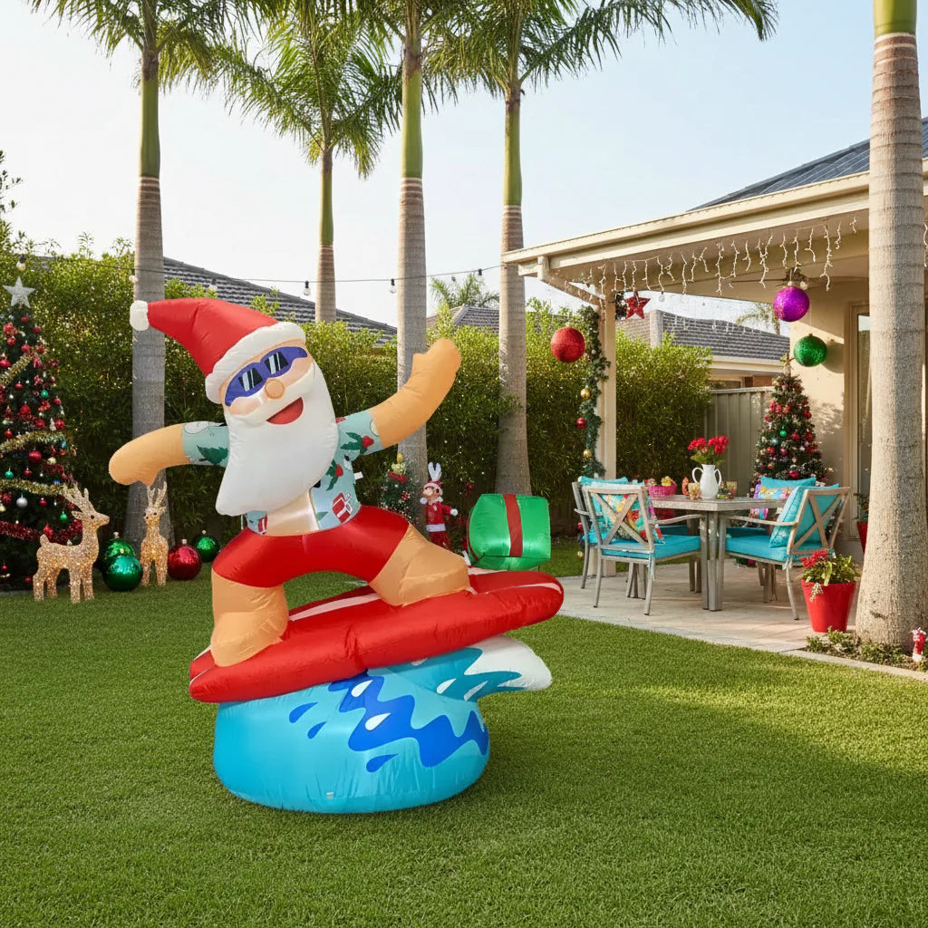 Inflatable Santa Claus character on a surfboard with a gift, on a white background