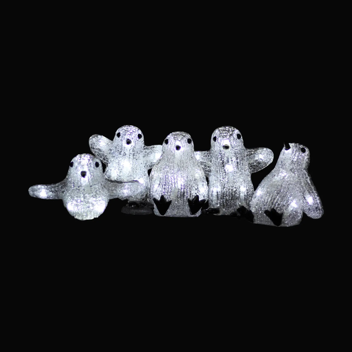 A line of five glittery acrylic led baby penguin figures with black feet and beaks in a 5pcs set illuminated display