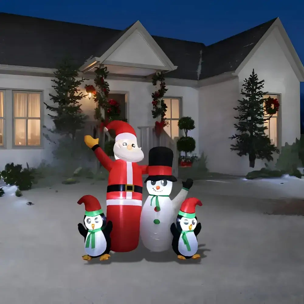 Inflatable Santa Claus with penguins in front of a house decorated for Christmas.