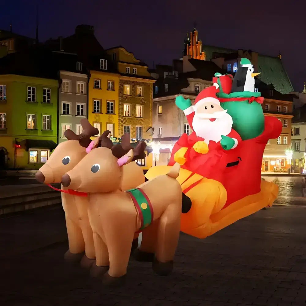 Inflatable Santa Claus in a sleigh with reindeer in front of a cityscape at night.