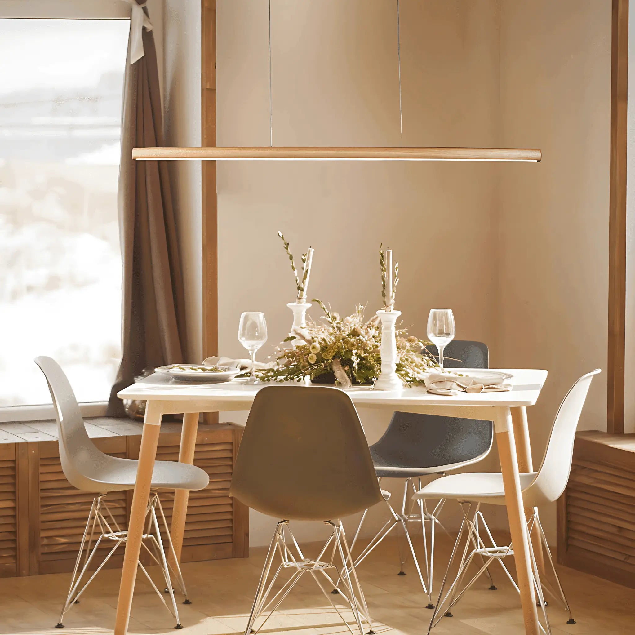 White rectangular dining table with wooden legs and beige and gray eames-style shell chairs under lexi lighting freya led pendant