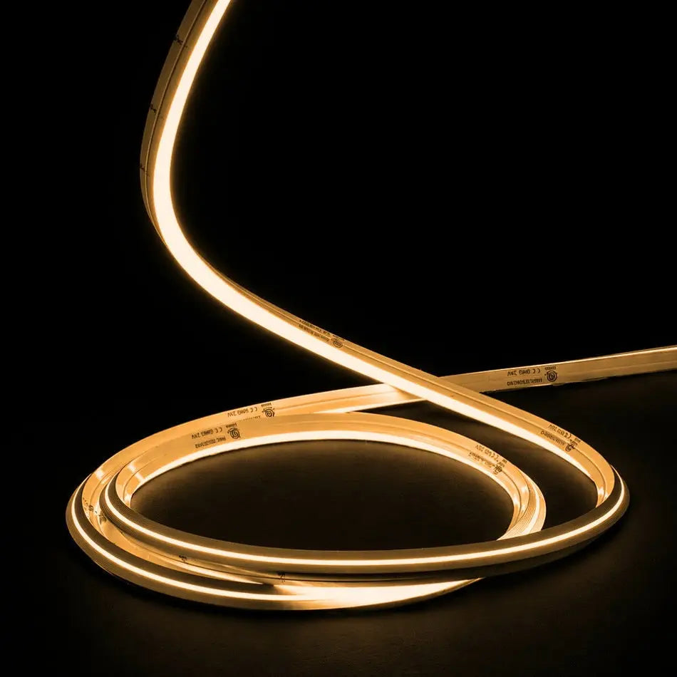 A flexible warm white LED light strip coiled on a black background, glowing brightly with a soft golden light.