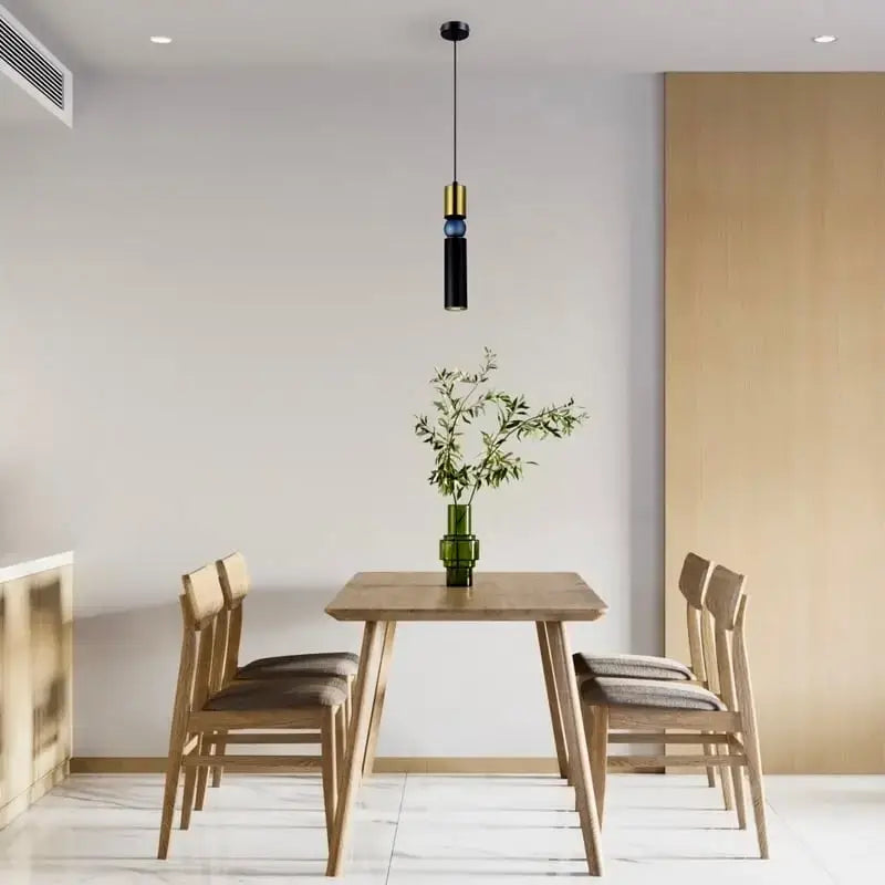 Modern dining room with wooden table and chairs, pendant light, and decorative plant. Roma Matt Black & Brass LED Tri-Colour Single Pendant Light
